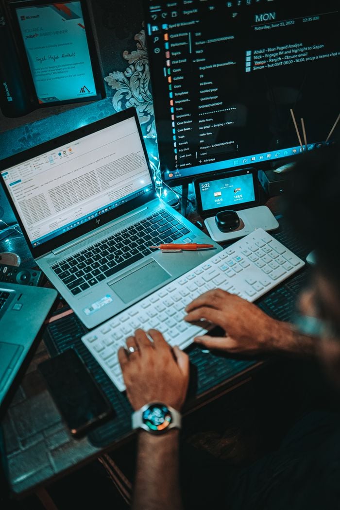 Close-up of hands typing on a keyboard while working at a computer.
